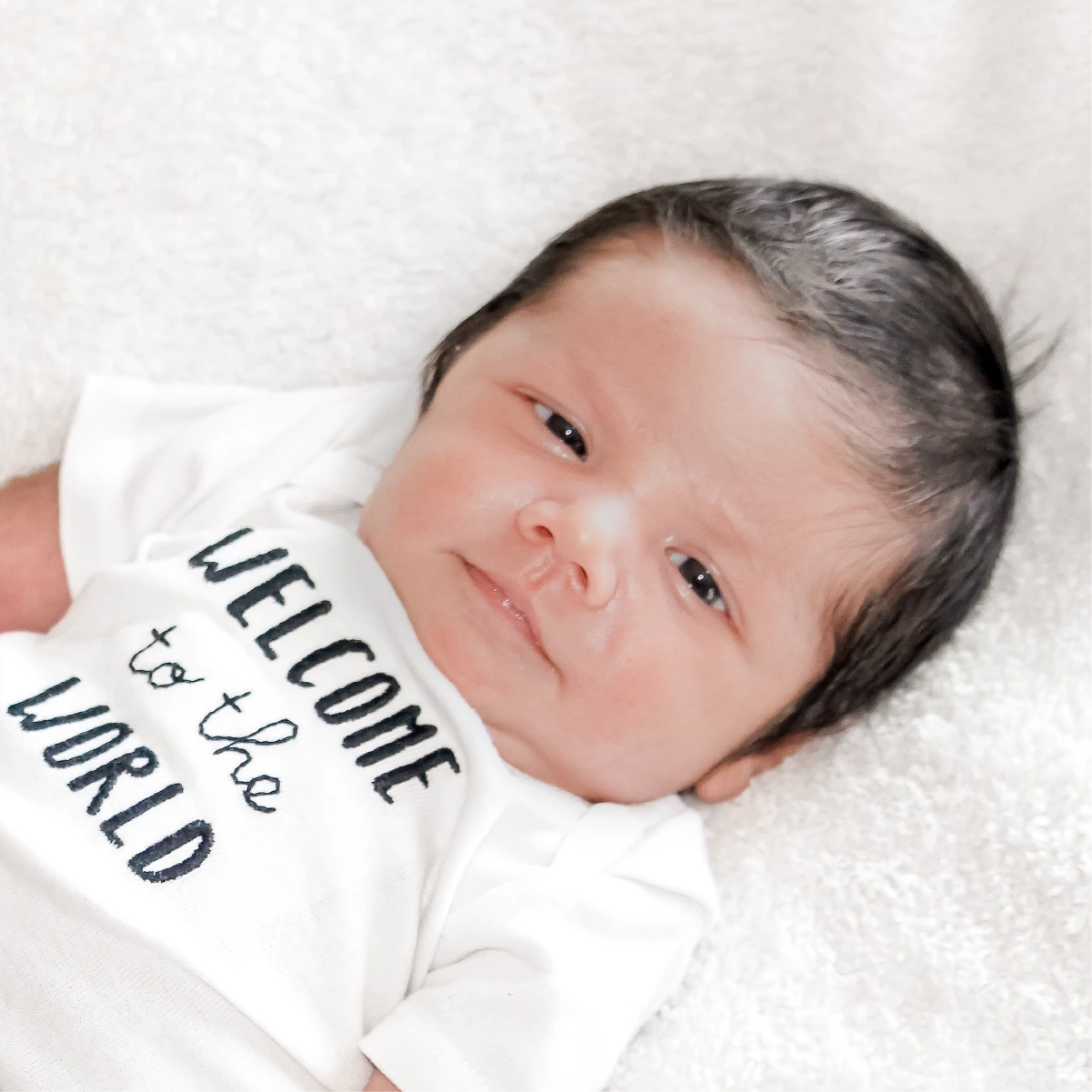 Newborn baby wearing a Welcome to the World onesie